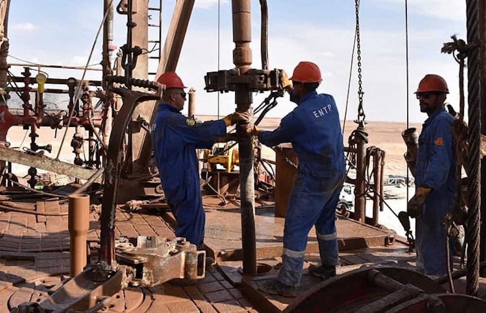 Employés de l’ENTP manipulant du matériel de forage sur un site pétrolier en Algérie.